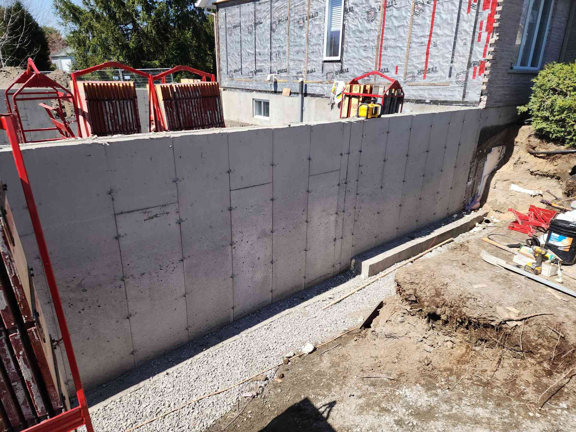 Mur décoffré et bande de gravier drainant courant le long de la semelle neuve