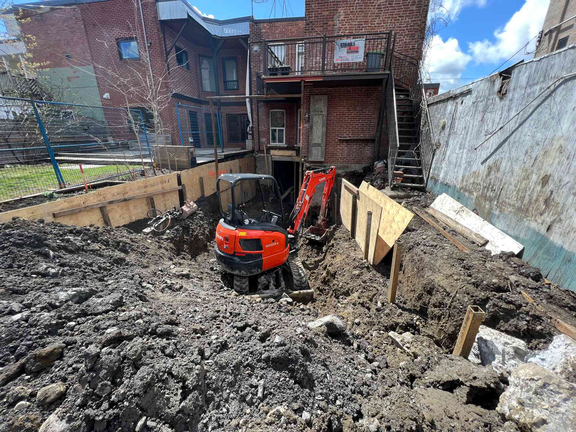 Mini-excavatrice creusant la cour arrière pour l'agrandissement du sous-sol