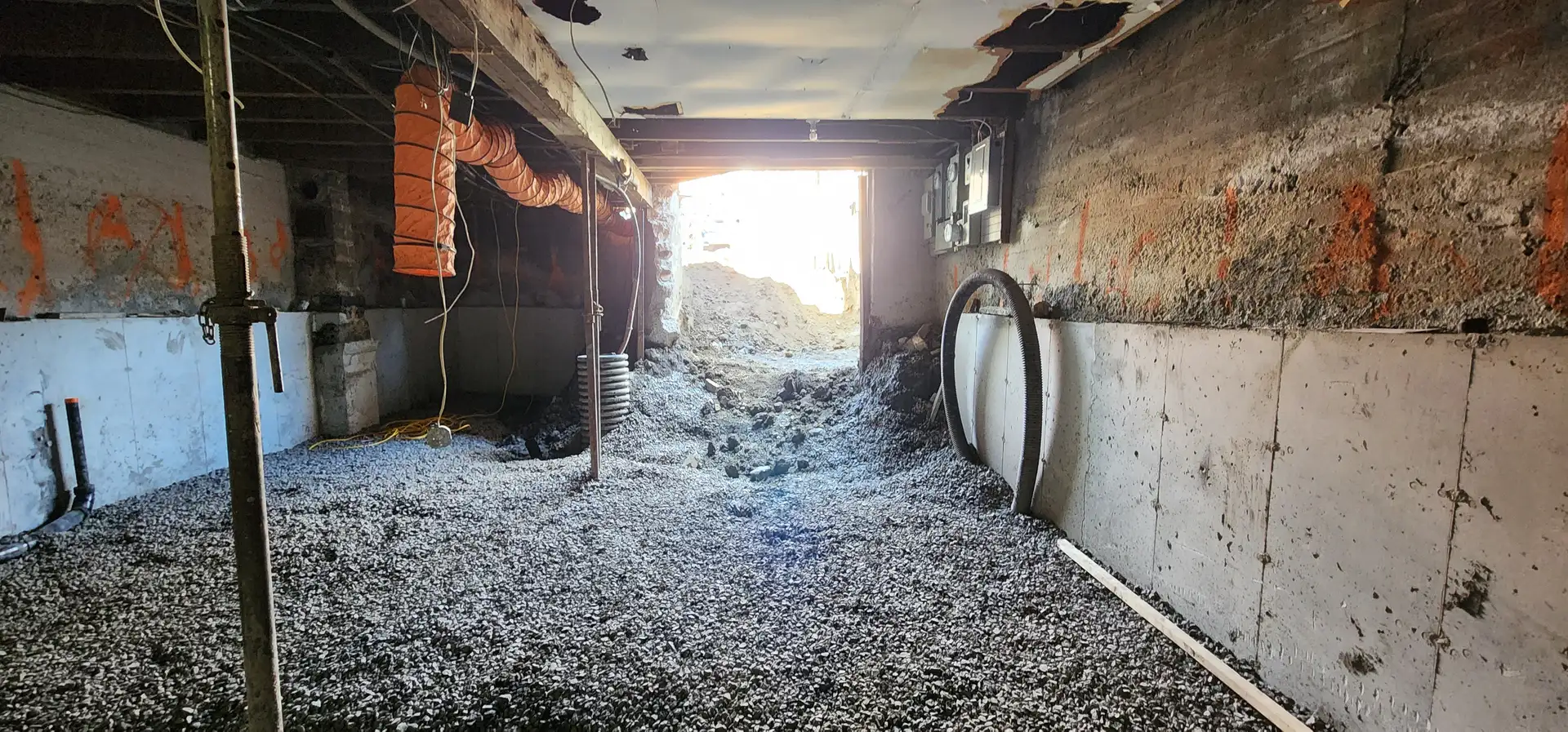 Sous-sol excavé rempli de gravier avec tuyau de drain déposé le long du mur
