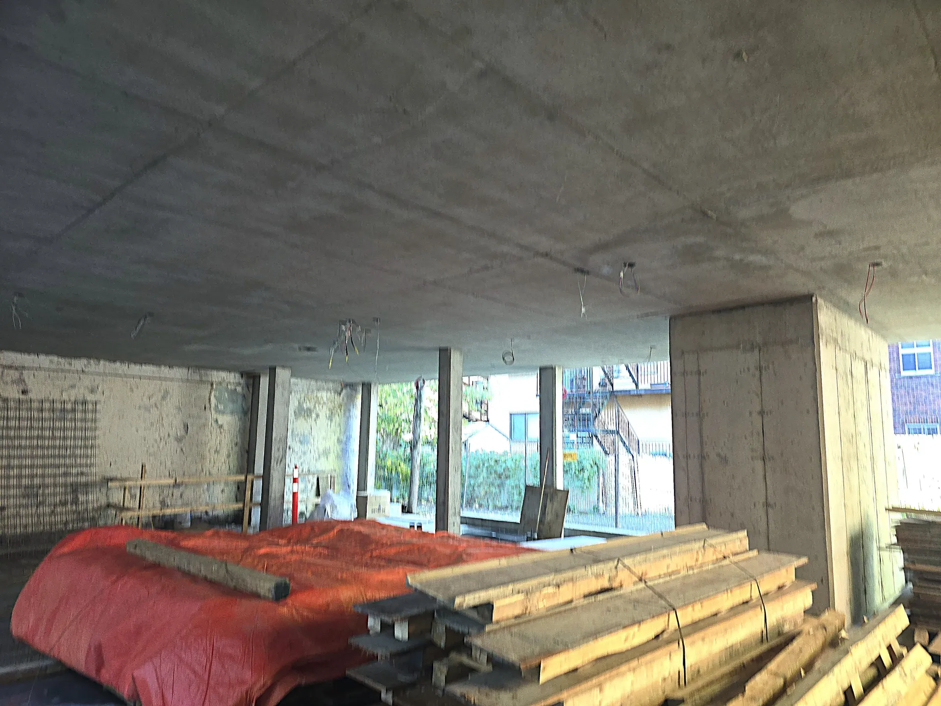 Dalle structurale | Stabili Pieux Sous-face lisse d'une dalle de béton terminée, colonnes et bois de coffrage empilé au sol