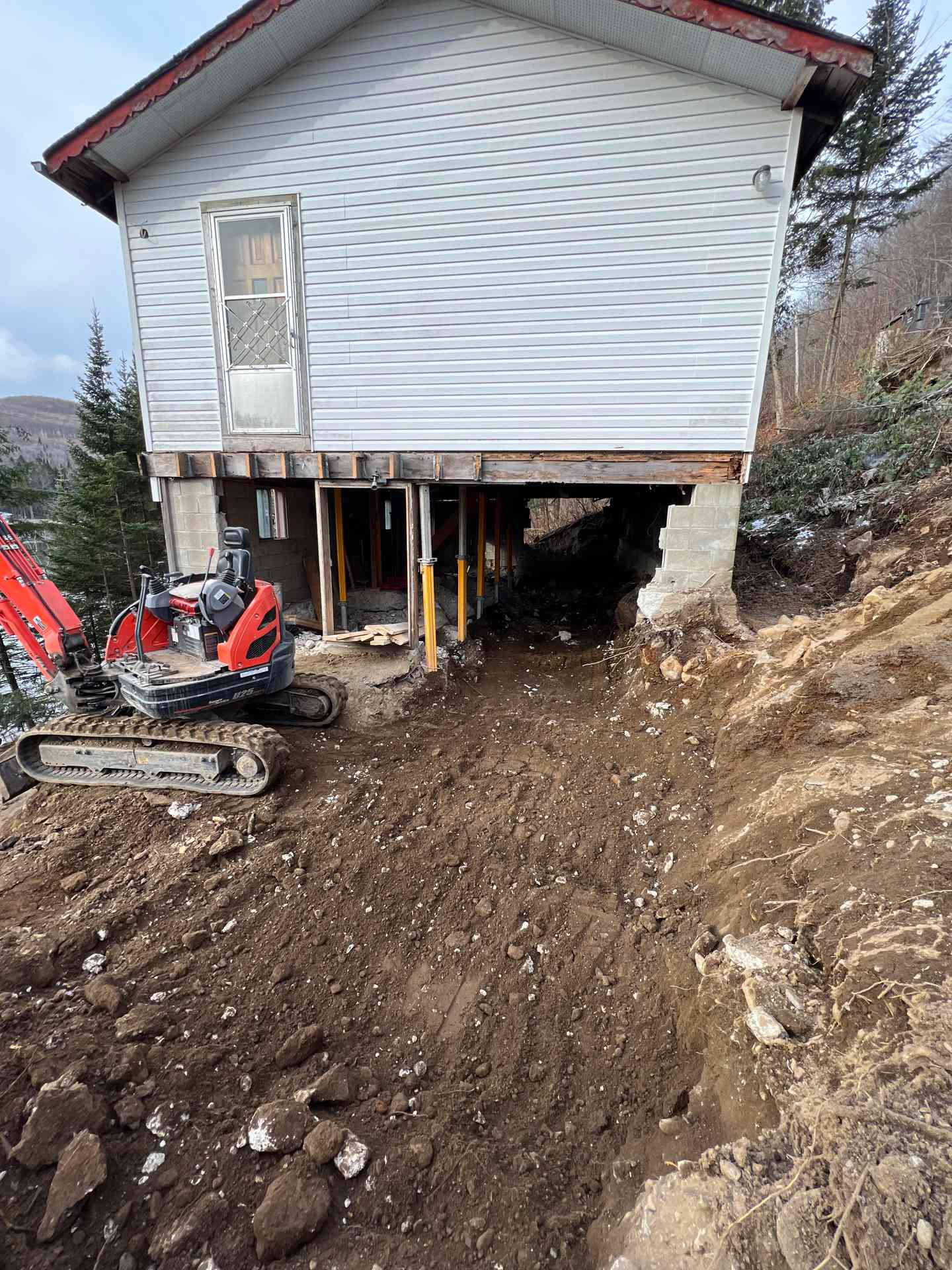 Mini-pelle et monticule de terre devant la maison temporairement soutenue