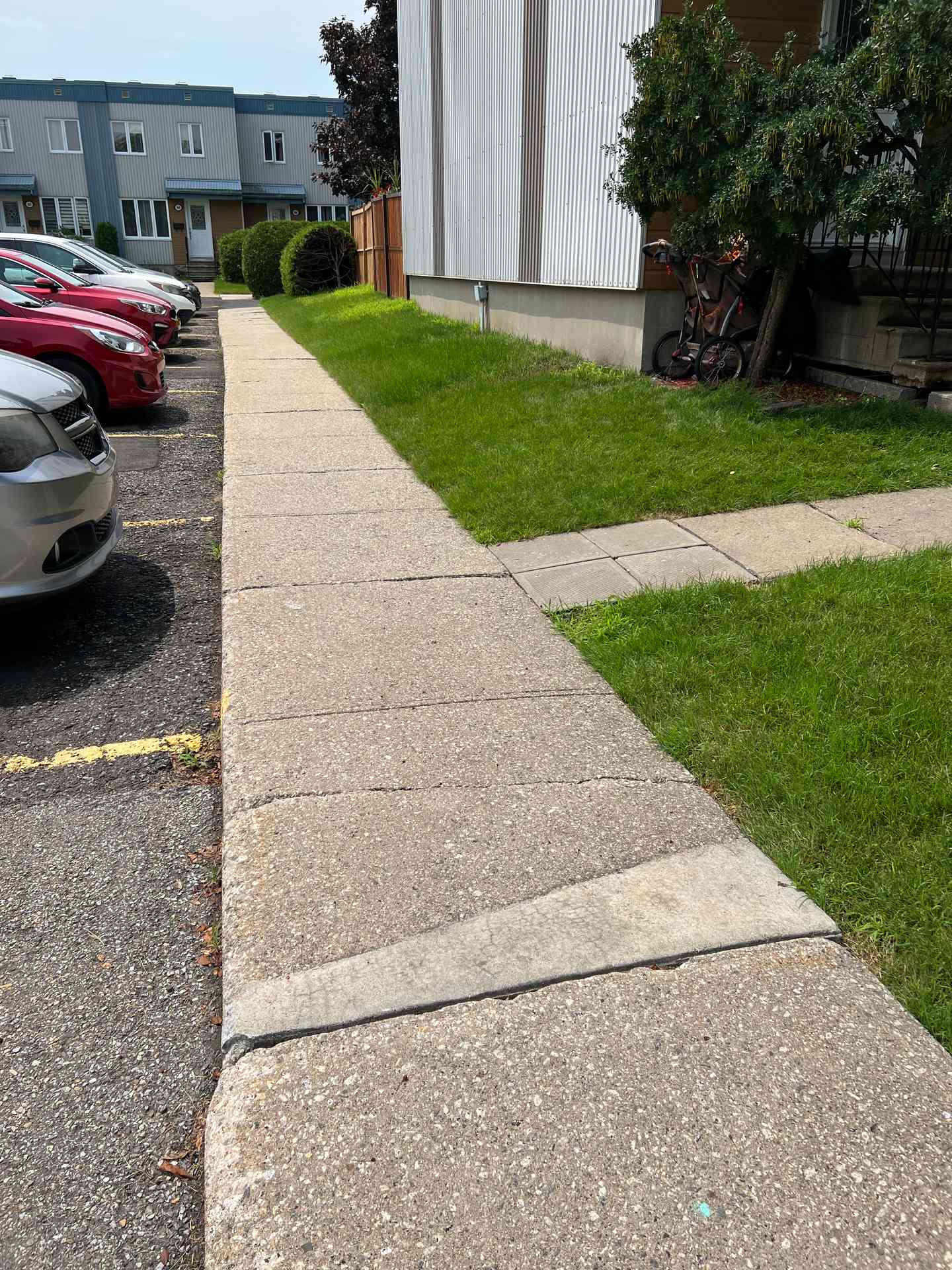 Trottoir de béton | Stabili Pieux Bordure de trottoir de béton longeant un bâtiment, voitures stationnées à l'arrière-plan